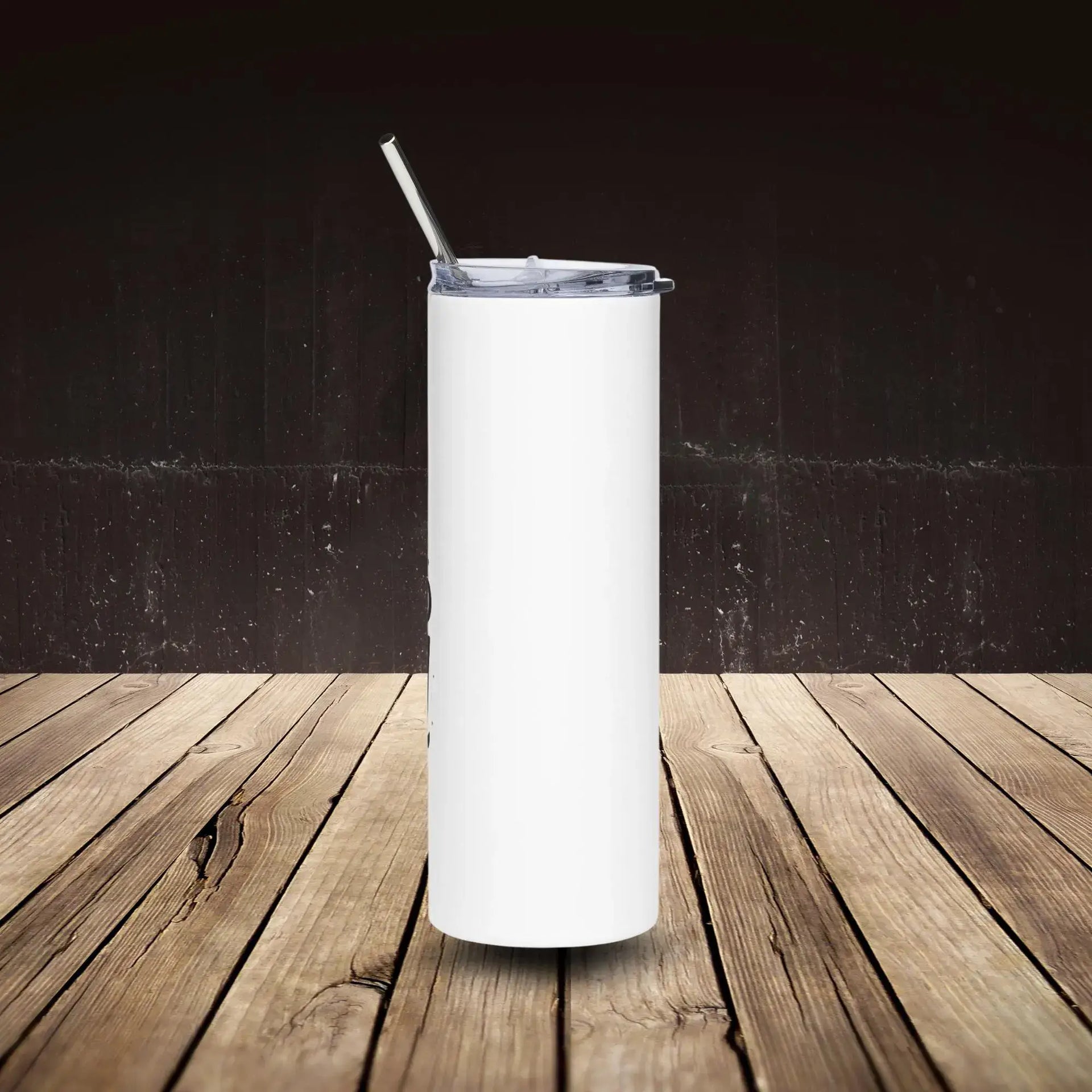 White tumbler with a straw on a wooden surface against a dark background