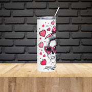 Tumbler with skull design and hearts on a wooden surface with a black brick wall background