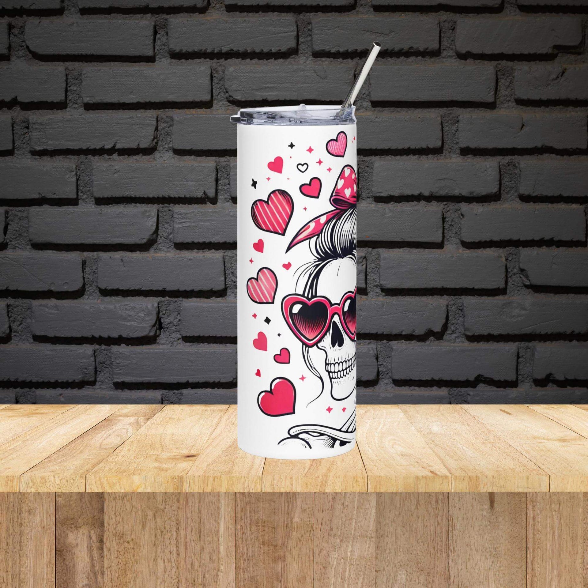 Tumbler with skull design and hearts on a wooden surface with a black brick wall background