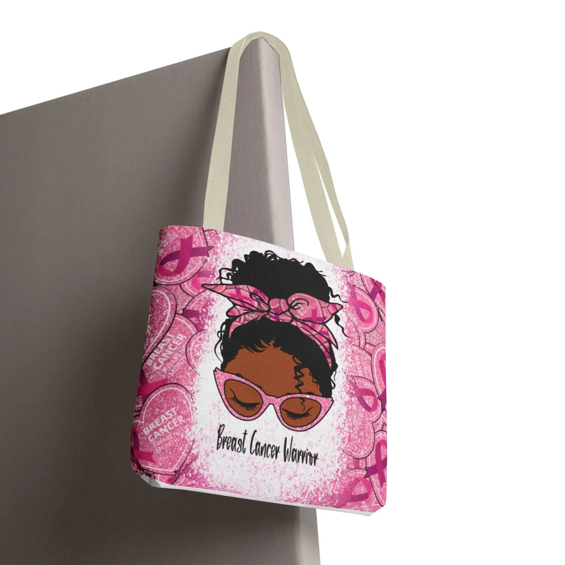 Pink tote bag with a graphic of a woman wearing sunglasses and a headband, with 'Breast Cancer Warrior' text, on a gray background.