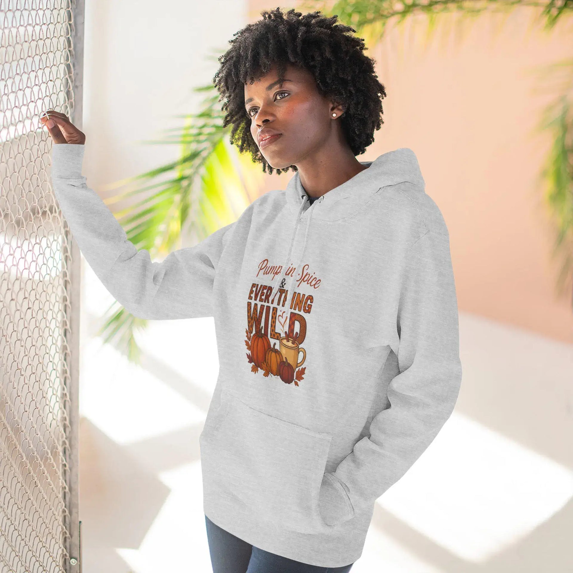 Person wearing a gray hoodie with a graphic design, standing indoors with plants in the background.