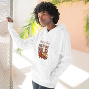 Person wearing a white hoodie with a graphic design, standing against a light-colored wall with plants.